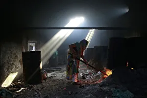 A woman lights fire to heat water for soaking clothes at a laundry in Mumbai A woman lights fire to heat water for soaking clothes at a laundry in Mumbai