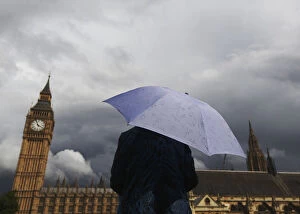 A woman looks towards dark clouds over the Houses of Parliament in central London
