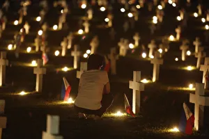 A woman offers a prayer near the grave of her loved one in a cemetery during the A woman offers a prayer near the grave of her loved one in a cemetery during the
