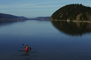 A woman paddles her kayak on the Lac de Joux on a sunny morning in Le Pont A woman paddles her kayak on the Lac de Joux on a sunny morning in Le Pont