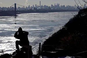A woman photographs ice on the Hudson River, with the George Washington Bridge A woman photographs ice on the Hudson River, with the George Washington Bridge