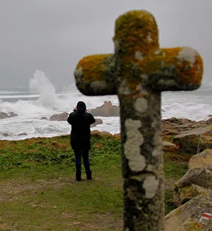 A woman photographs waves breaking on the Brittany coast after storm Eleanor hit A woman photographs waves breaking on the Brittany coast after storm Eleanor hit