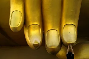 A woman prays while touching the fingers of a Buddha statue during the annual Makha Bucha A woman prays while touching the fingers of a Buddha statue during the annual Makha Bucha