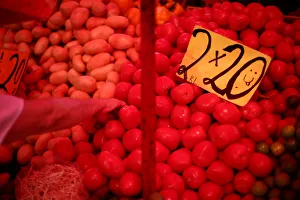 A woman selects vegetables next to sign that displayed the price of tomatoes at a store A woman selects vegetables next to sign that displayed the price of tomatoes at a store