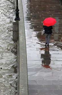 A woman shelters under her umbrella as she walks alongside the River Thames during A woman shelters under her umbrella as she walks alongside the River Thames during