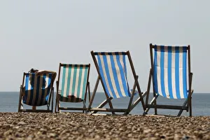 A woman sunbathes in a deckchair by the sea on a sunny day on Brighton Beach in southern A woman sunbathes in a deckchair by the sea on a sunny day on Brighton Beach in southern