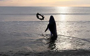 A woman throws a wreath into the water during a procession of the Santisimo Cristo del A woman throws a wreath into the water during a procession of the Santisimo Cristo del