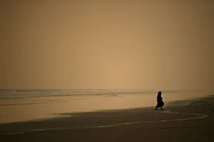A woman walks along the beach at sunset in Coxs Bazar A woman walks along the beach at sunset in Coxs Bazar
