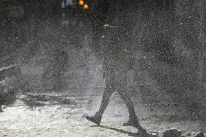 A woman walks through a gust of blowing snow in frigid cold temperatures though downtown A woman walks through a gust of blowing snow in frigid cold temperatures though downtown
