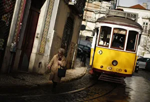 A woman walks near a tram at the Alfama neighborhood in Lisbon A woman walks near a tram at the Alfama neighborhood in Lisbon