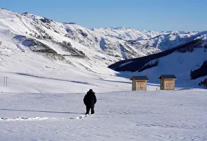 A woman walks toward a toilet among mountains covered with snow in Hemu of Altay A woman walks toward a toilet among mountains covered with snow in Hemu of Altay