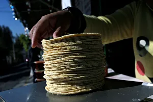 Woman weighs a stack of freshly made corn tortillas at factory in Mexico City Woman weighs a stack of freshly made corn tortillas at factory in Mexico City