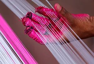 A worker applies colour to strings which will be used to make kites A worker applies colour to strings which will be used to make kites