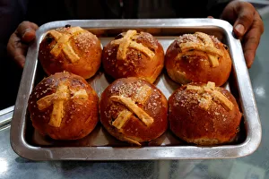 A worker holds a tray of cross fruit buns, traditionally prepared A worker holds a tray of cross fruit buns, traditionally prepared