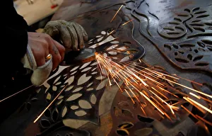 A worker uses an angle grinder on a piece of metal at a steel workshop in Marseille A worker uses an angle grinder on a piece of metal at a steel workshop in Marseille