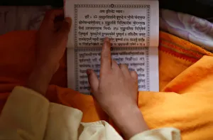 A young Hindu priest reads a holy book with prayers written on it during the Janai A young Hindu priest reads a holy book with prayers written on it during the Janai
