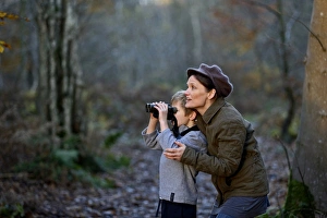 Mother showing son birds in woodland in autumn Norfolk Mother showing son birds in woodland in autumn Norfolk