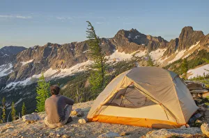 Adult man at daybreak sitting next to backpacking tent and gazing at view of Cutthroat Adult man at daybreak sitting next to backpacking tent and gazing at view of Cutthroat