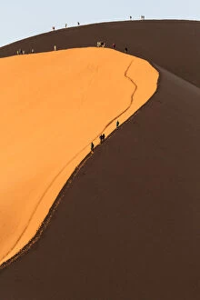 Images Dated 21st September 2013: Africa, Namib Desert. Hikers climbing the red sand dune in Namibia