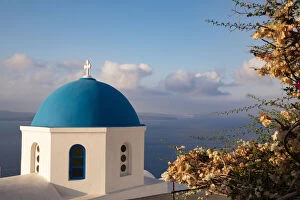 Aegean Sea Gallery: Blue domed Greek Orthodox church with bougainvillea flowers in Oia, Santorini, Greece