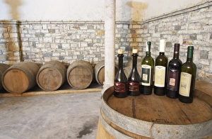 Bottles on top of a barrel, with barriques in the background Bottles on top of a barrel, with barriques in the background
