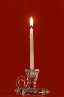 Burning candle in a glass candle holder on red background Burning candle in a glass candle holder on red background