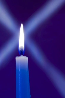 Burning candle with star burst on blue background Burning candle with star burst on blue background