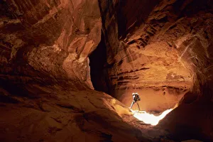 Canyoneer illuminated in the depths of a narrow canyon in the Dirty Devil Canyon Canyoneer illuminated in the depths of a narrow canyon in the Dirty Devil Canyon