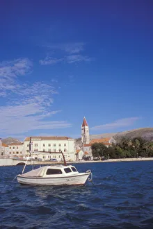 The Cathedral of Saint Lovro in Trogir stands behind a small boat in the Trogir Canal The Cathedral of Saint Lovro in Trogir stands behind a small boat in the Trogir Canal