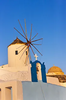 Church bell tower and windmill on the coast of Aegean Sea. Oia, Santorini Island, Greece Church bell tower and windmill on the coast of Aegean Sea. Oia, Santorini Island, Greece