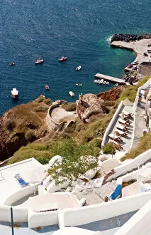 Step Collection: Along the cliff of Oia, view the boats docked in the water, Greece