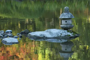Concrete lantern on a rock in a pond surrounded by reflections of Fall colors in the water Concrete lantern on a rock in a pond surrounded by reflections of Fall colors in the water