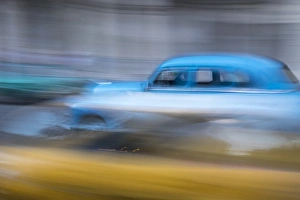 Cuba, Havana. Classic cars speed by in a blur along the streets of the city Cuba, Havana. Classic cars speed by in a blur along the streets of the city