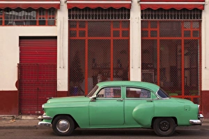 Cuba, Havana. Green car, red building on the streets Cuba, Havana. Green car, red building on the streets