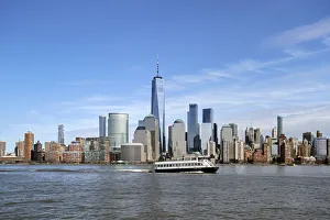 A ferry on the Hudson River passes by One World Trade Center and Manhattan buildings A ferry on the Hudson River passes by One World Trade Center and Manhattan buildings
