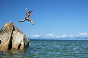 Girl jumping off rock, Mosquito Bay, Abel Tasman National Park, Nelson Region, South Island Girl jumping off rock, Mosquito Bay, Abel Tasman National Park, Nelson Region, South Island