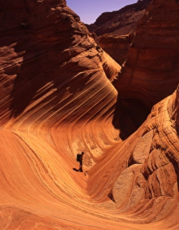 Hiker enjoys swirling Navajo Sandstone, Vermillion Cliffs area, Arizona Hiker enjoys swirling Navajo Sandstone, Vermillion Cliffs area, Arizona