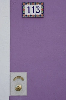 Italy, Burano. Purple stucco wall with white tile house number and brass doorbell button Italy, Burano. Purple stucco wall with white tile house number and brass doorbell button