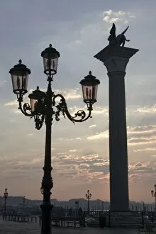 Images Dated 13th March 2005: Italy, Venice. Lion of St. Mark atop column and ornate lamp at sunrise