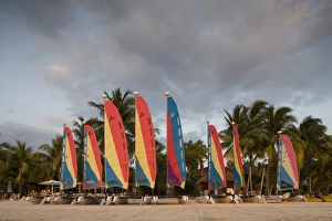 Jamaica, Negril, Setting sun lights row of sailboats at tourist resort along white Jamaica, Negril, Setting sun lights row of sailboats at tourist resort along white