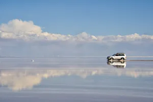 Jeep driving on the reflected surface of the salt flat, Salar de Uyuni, Potosi Department Jeep driving on the reflected surface of the salt flat, Salar de Uyuni, Potosi Department