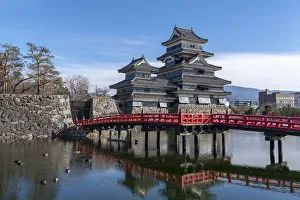 The Matsumoto Castle as seen from the bridge with the city buildings in the background The Matsumoto Castle as seen from the bridge with the city buildings in the background