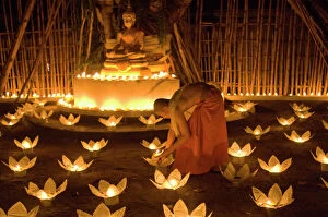 Monastery Collection: Monks lighting khom loy candles and lanterns for Loi Krathong festival