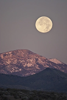 Full moon setting over snow-covered Magdelena Mountains at Socorro, New Mexico Full moon setting over snow-covered Magdelena Mountains at Socorro, New Mexico