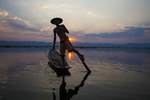 Myanmar, Inle Lake. Fisherman rowing at sunset Myanmar, Inle Lake. Fisherman rowing at sunset