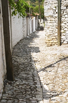 A narrow cobble stone street lined with white stone houses A narrow cobble stone street lined with white stone houses