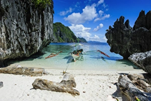 Outrigger boat on a little white beach and crystal clear water in the Bacuit archipelago Outrigger boat on a little white beach and crystal clear water in the Bacuit archipelago