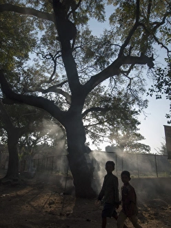 Pedestrians pass burning leaves in Bijapur, Karntaaka, India Pedestrians pass burning leaves in Bijapur, Karntaaka, India