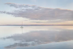 Sailboat and morning clouds reflected in calm waters of Bellingham Bay, Washington State Sailboat and morning clouds reflected in calm waters of Bellingham Bay, Washington State