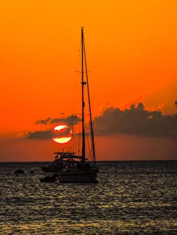 Seven Mile Beach, Grand Cayman. Sailboat and a boat with the orange sun setting behind